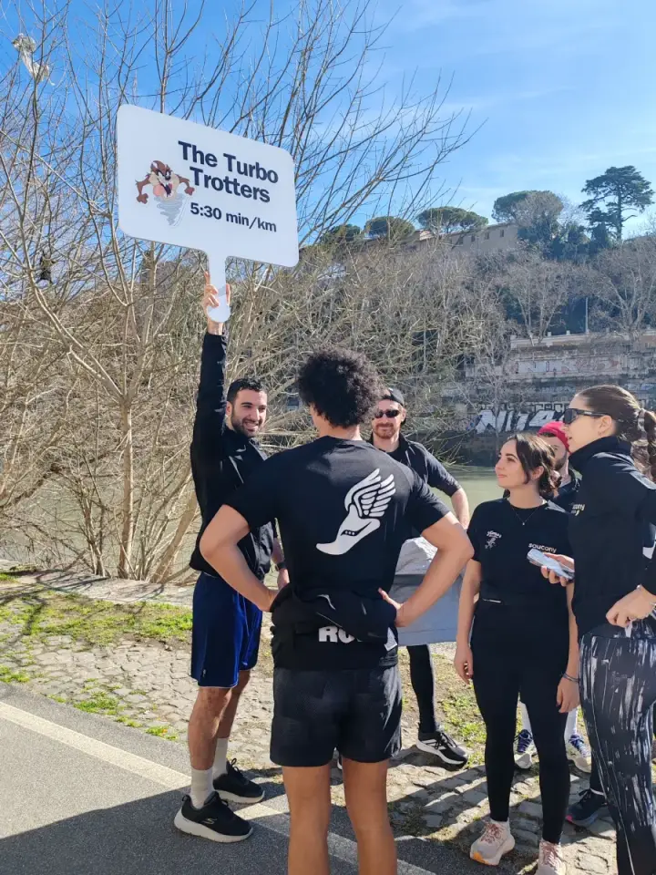 Andrea holding up the 5:30 min/km pace sign with his running group by the Tiber